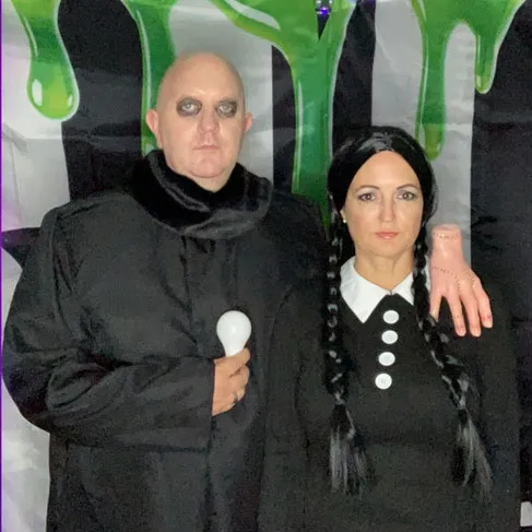 Man and woman dressed as Uncle Fester and Wednesday Addams